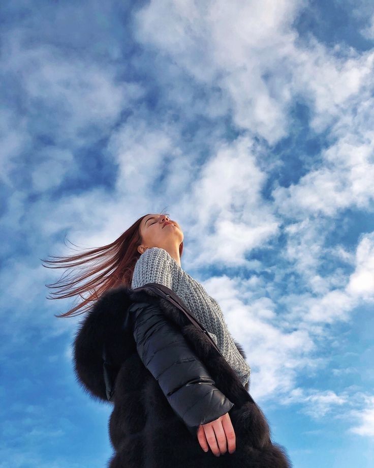 a woman is looking up into the sky with her hair blowing in the wind,