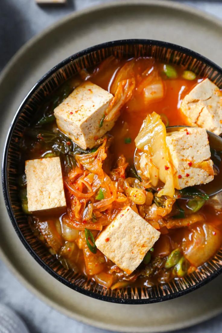 a bowl filled with tofu and vegetables on top of a table