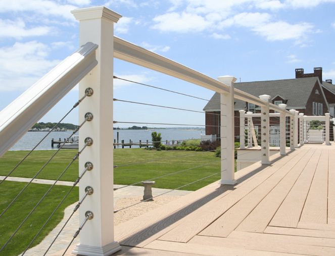 a wooden deck with white railings next to a house