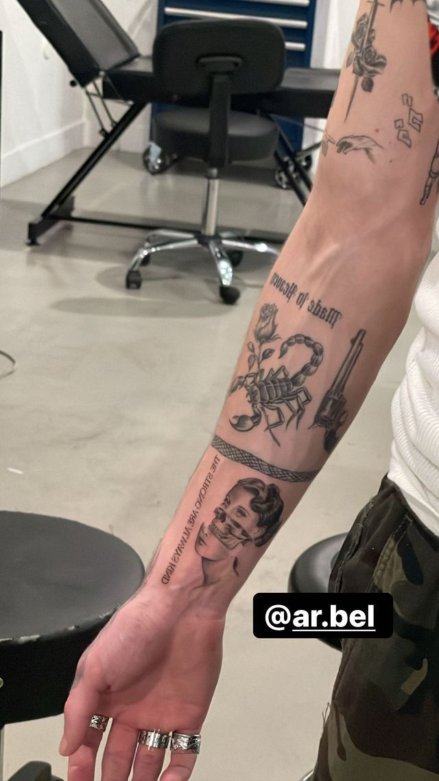 a man's arm with tattoos on it in front of a chair and desk