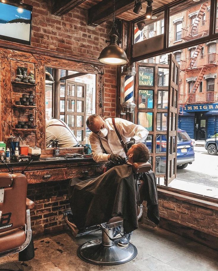 a man getting his hair cut at a barber shop in front of a large window