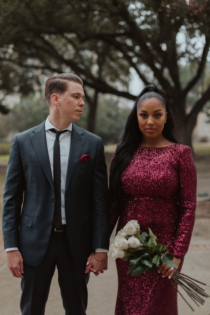 a man and woman standing next to each other holding hands