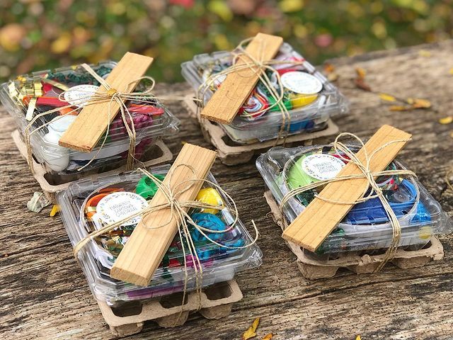 four small boxes filled with different types of crafting supplies on a wooden table outdoors