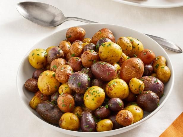 a white bowl filled with potatoes on top of a table next to silver spoons