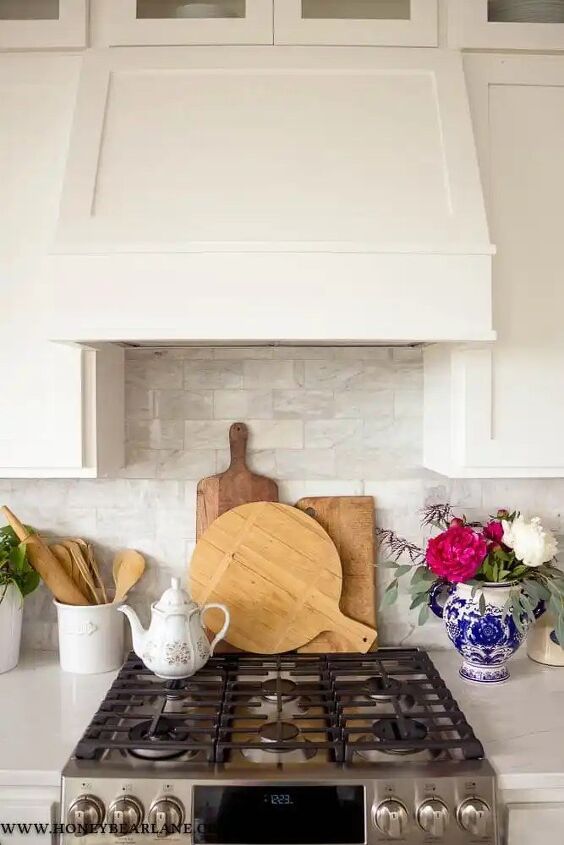 a stove top oven sitting inside of a kitchen next to a vase filled with flowers