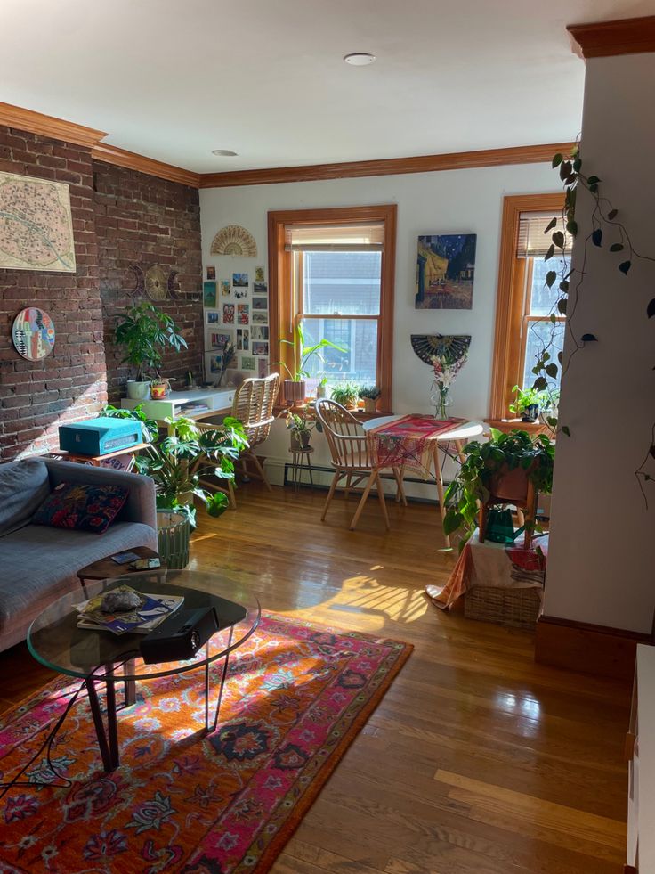 a living room filled with furniture and lots of plants on top of a hard wood floor