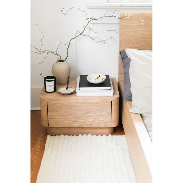 a bed room with a neatly made bed and a plant on top of the night stand