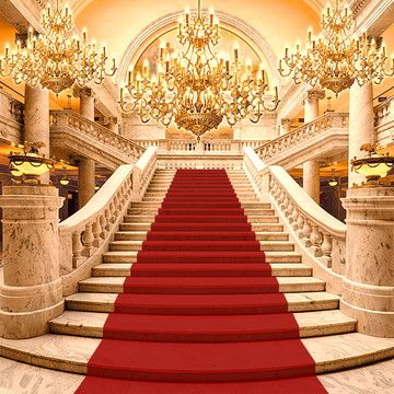 a red carpeted staircase with chandelier and chandeliers