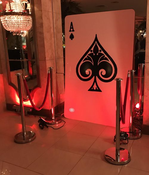 a casino room with red lighting and playing cards on the wall in front of it