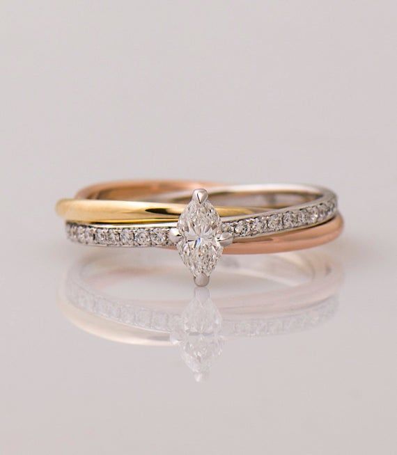 two gold and white diamond wedding rings on a reflective surface