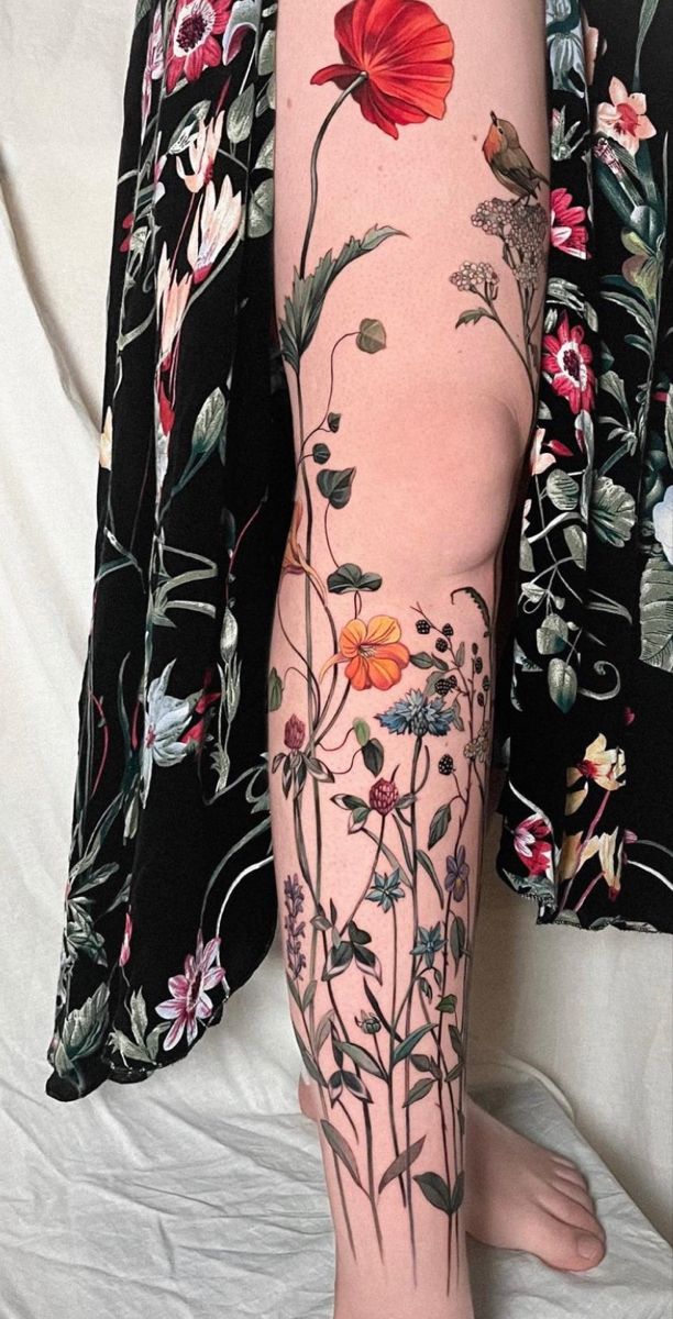 a woman's leg with flowers and leaves on it