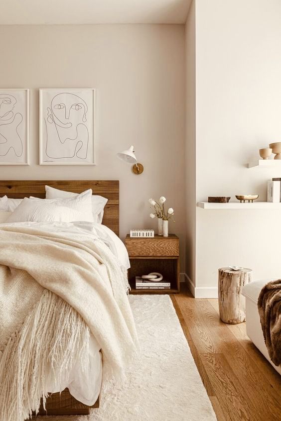 a bedroom with white walls and wooden flooring is pictured in this image, there are two pictures on the wall above the bed