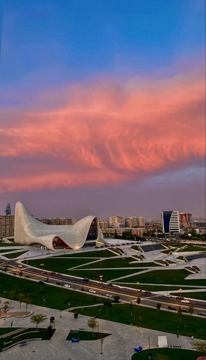 the sky is pink and blue with clouds in the back ground, and buildings on either side