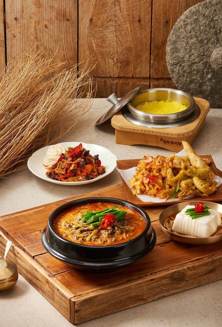 a table topped with plates of food next to a bowl of soup and other foods