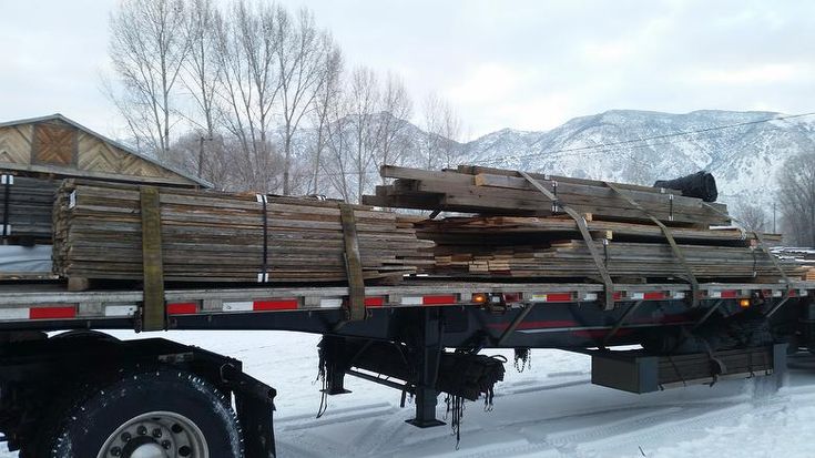 a large truck carrying logs in the snow