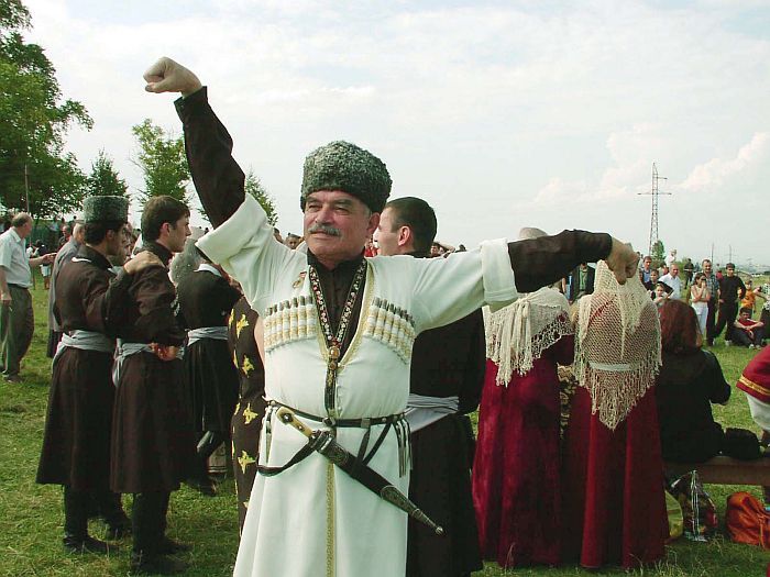 a man dressed in medieval clothing holding his arms up while standing next to other people