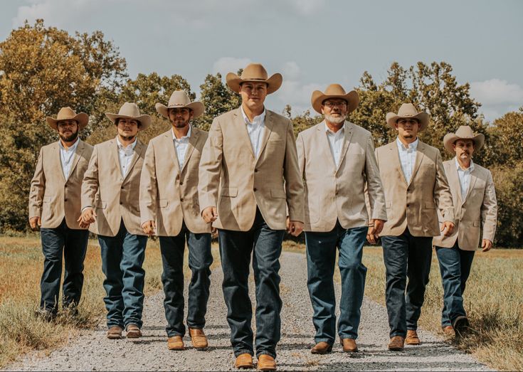 a group of men in suits and hats walking down a road