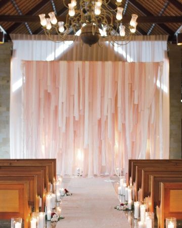 the aisle is lined with candles and decorated with pink draping for an elegant touch