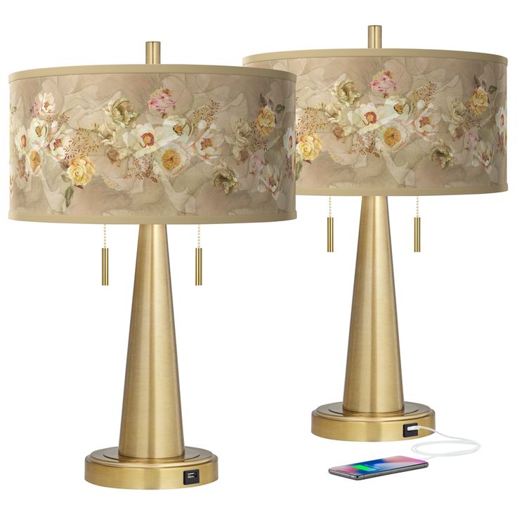 two lamps with flowers on them next to a charger and cell phone plugged in