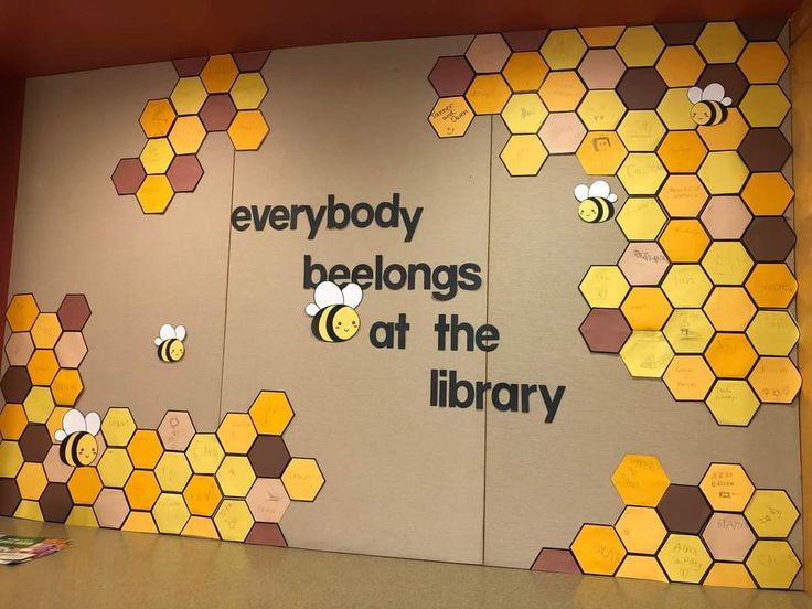 there is a wall with bees on it and the words everybody belongs at the library