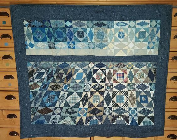 a blue and white quilt is hanging on a wall in a room with wooden drawers