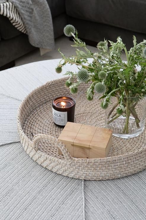 a table with a candle and some flowers on it in front of a gray couch