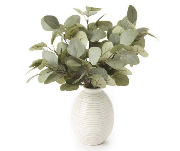 a white vase filled with lots of green leaves