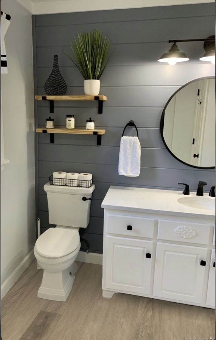 a white toilet sitting next to a sink in a bathroom under a mirror and lights