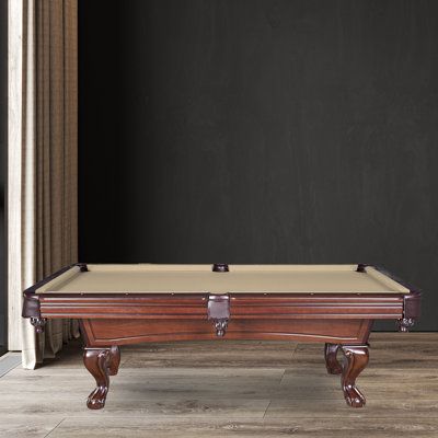 a pool table sitting on top of a hard wood floor next to a black wall