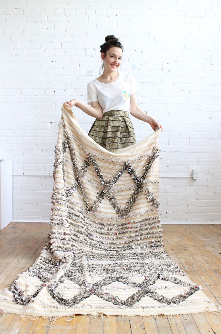 a woman standing on top of a wooden floor holding a blanket