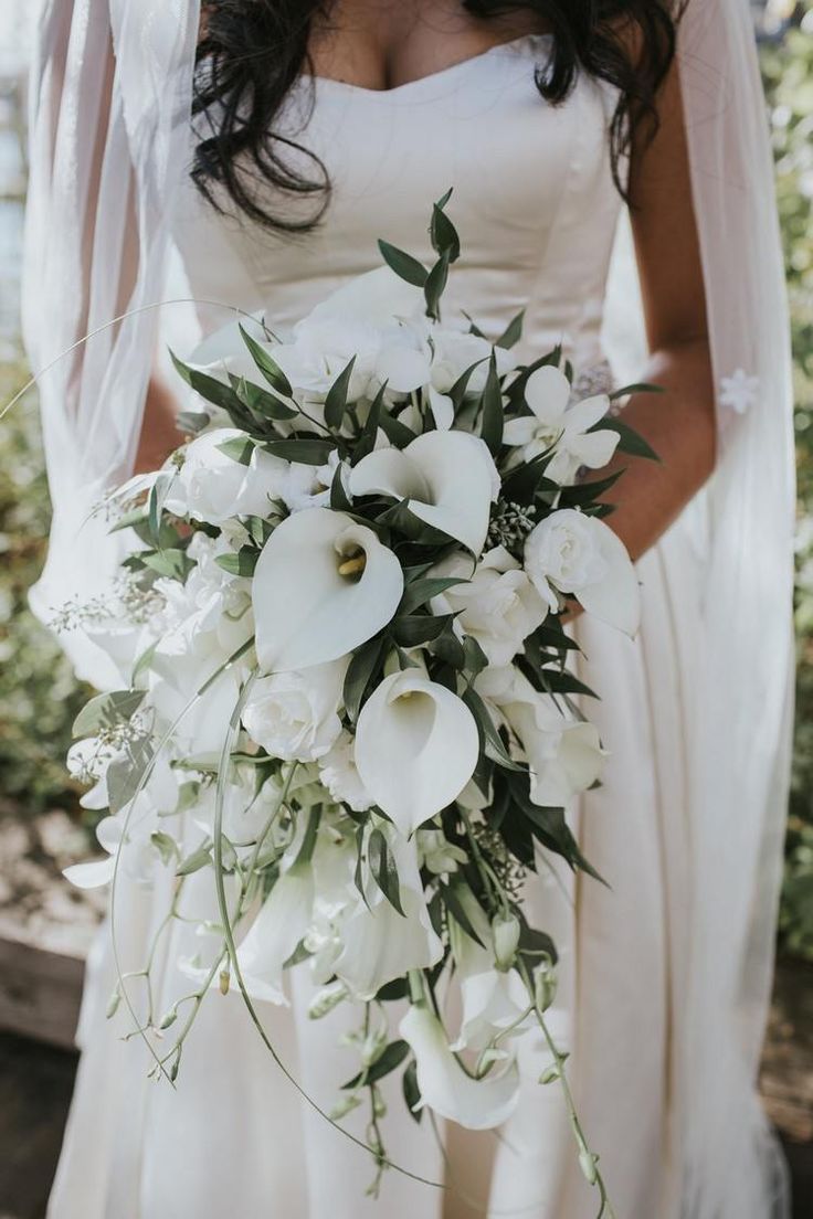 a bride holding a bouquet of white flowers