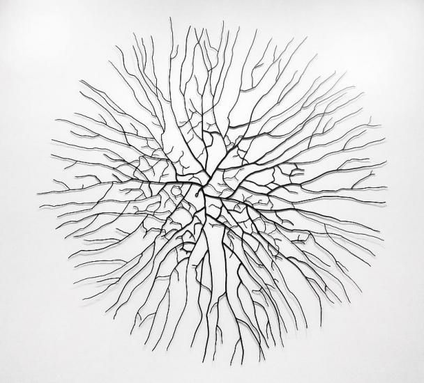 a metal wall sculpture with many branches in the shape of a circle on a white background