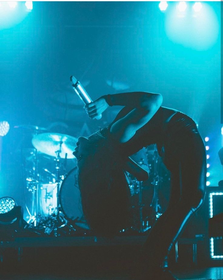 a man standing on top of a stage next to a drum set in front of him