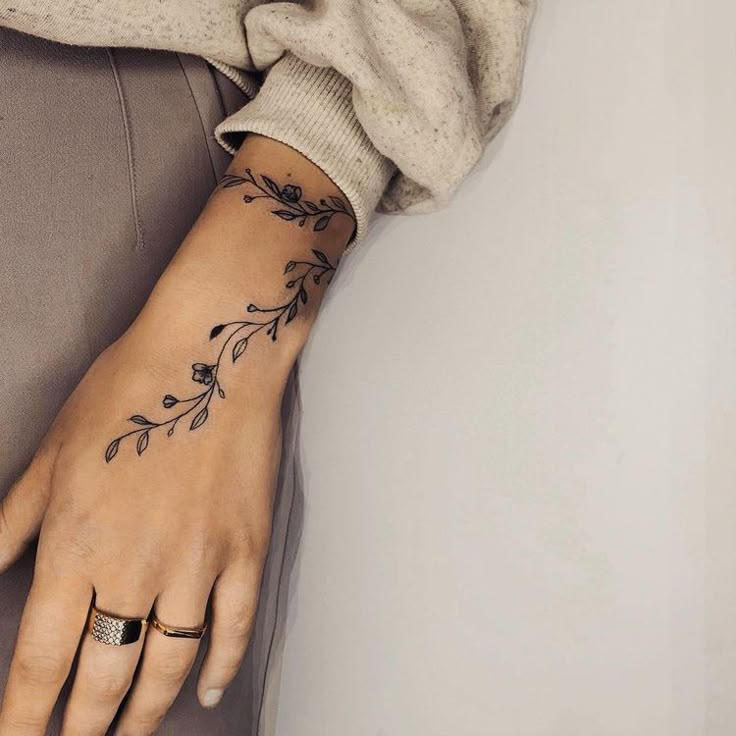 a woman's hand with a flower tattoo on her left wrist and the other arm