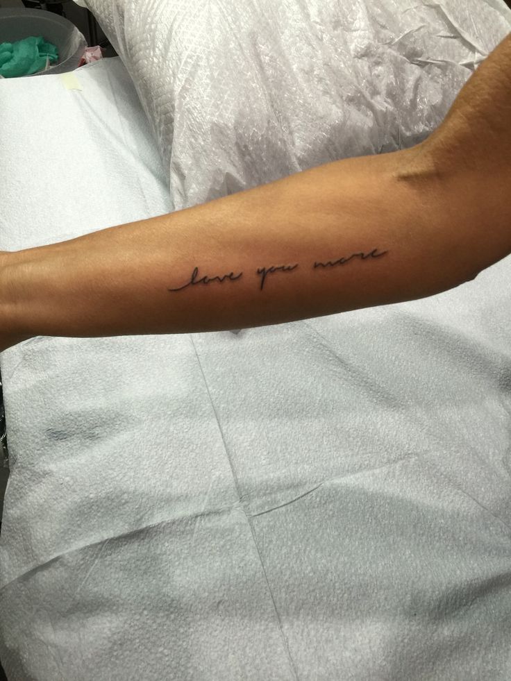 a man's arm with the words love you more on it in cursive font