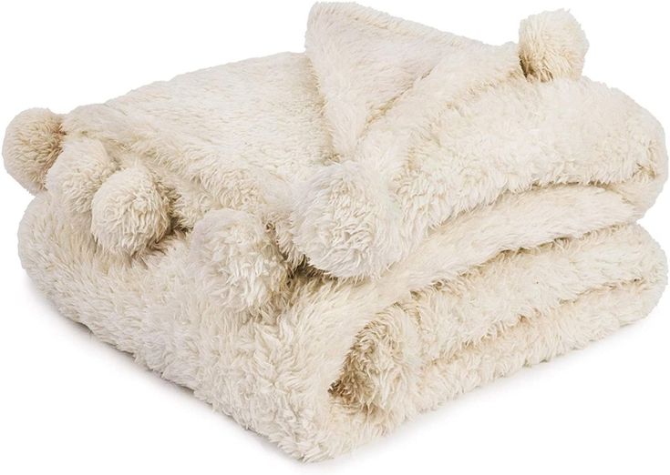 a white blanket with two pom poms on the top and one in the middle