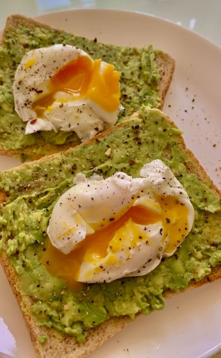 two pieces of bread with avocado and poached eggs on them sitting on a plate