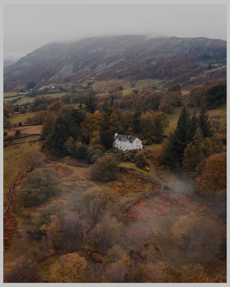 an aerial view of a white house in the middle of a field with trees on both sides