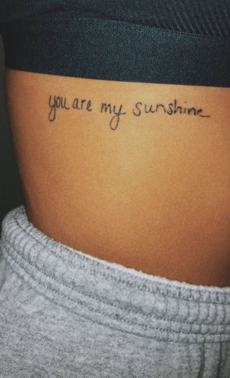 a woman's stomach with the words you are my sunshine tattooed on her side