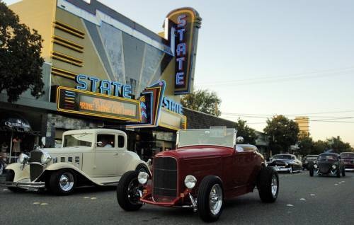 an old car is parked in front of a theater