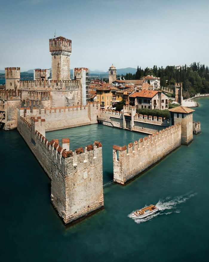 an aerial view of a castle on the water with a boat in it's foreground