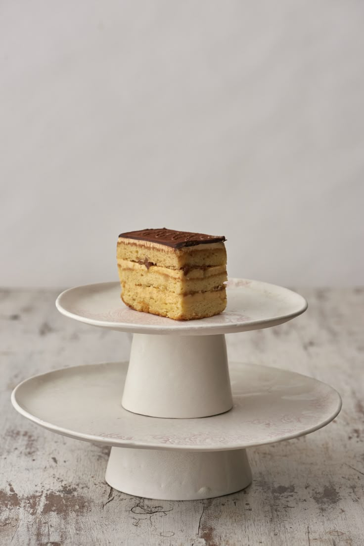 a piece of cake sitting on top of a white cake platter next to another plate