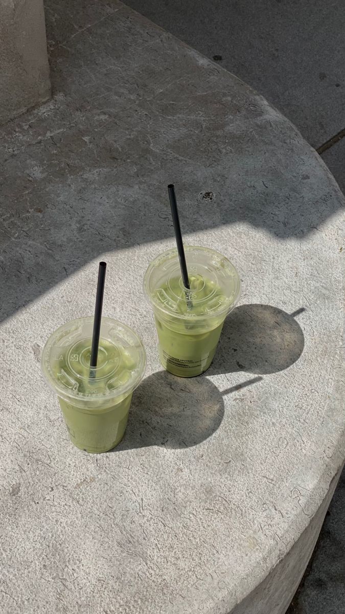 two green drinks sitting on top of a cement slab