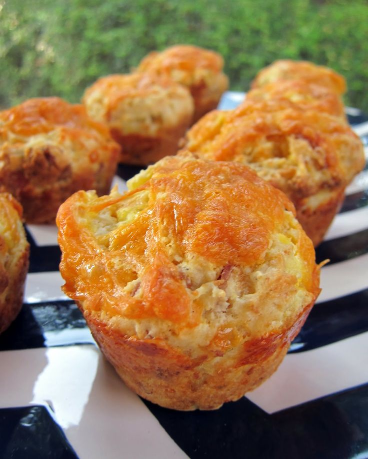 several small muffins are on a black and white striped plate with grass in the background