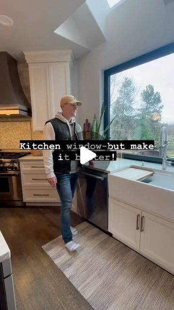 a man standing in front of a kitchen window next to a sink and dishwasher