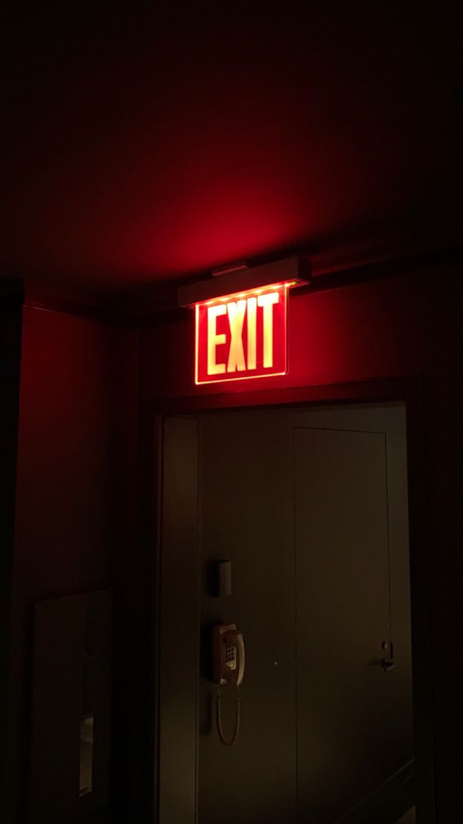 an exit sign lit up in the dark with red light coming from it's side