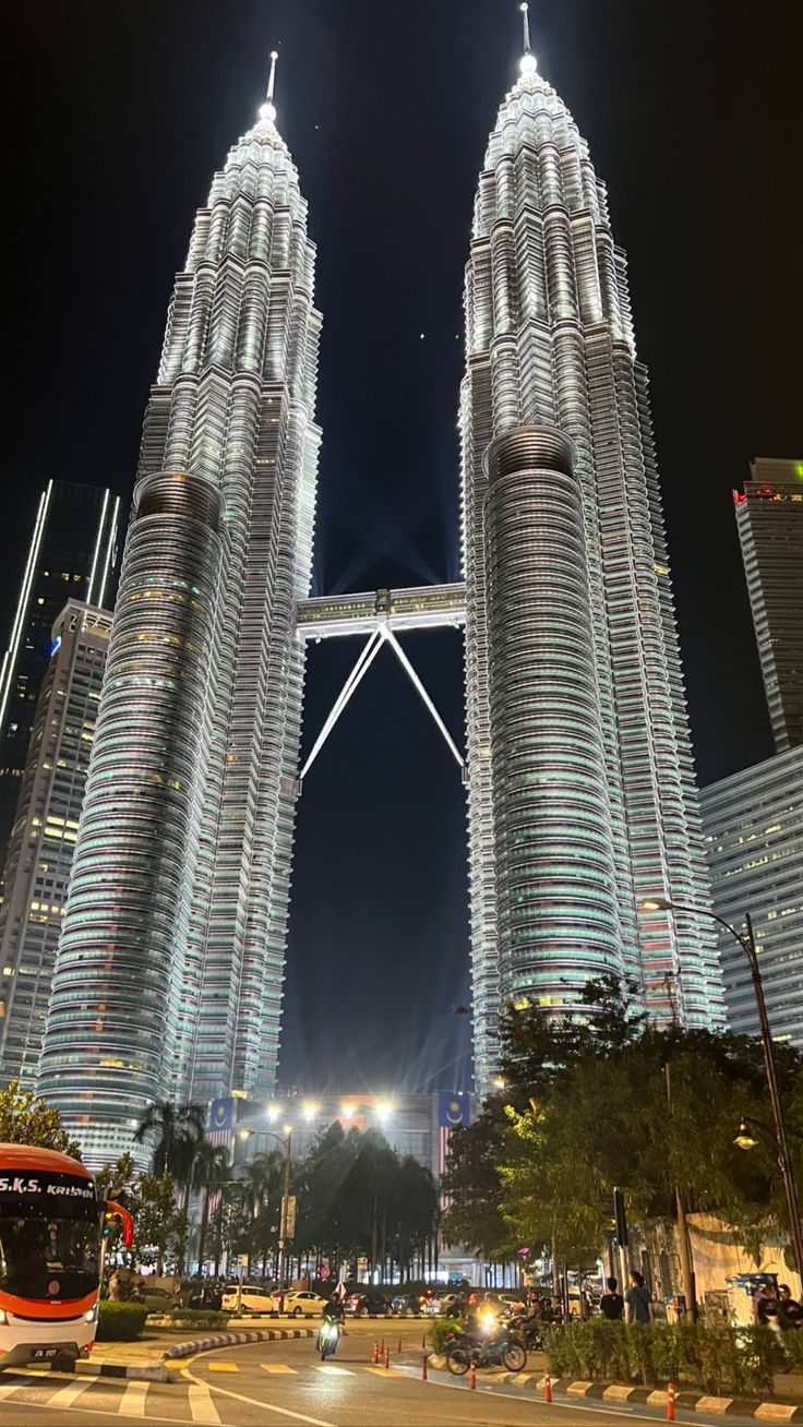 two very tall buildings towering over a city at night