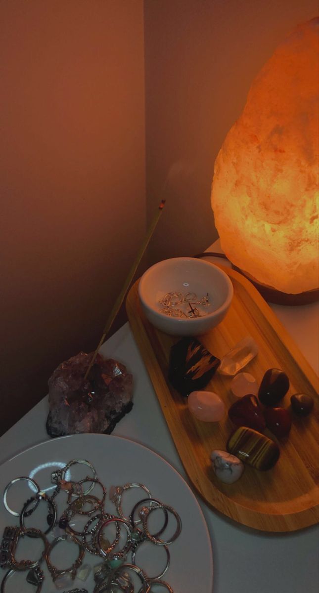 a table topped with lots of different types of jewelry next to a lit stone lamp