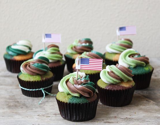 cupcakes with green frosting and an american flag on top are sitting on a table