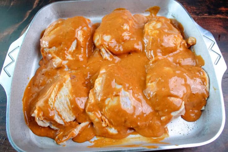 a pan filled with meat covered in gravy on top of a wooden table